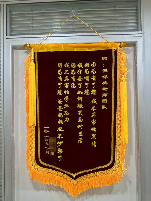 来访者赠伍群英老师团队的锦旗：因为有了您，我不再害怕黑暗；因为有了您，我学会了如何微笑面对生活；因为有了您，我不再害怕学业压力；因为有了您，爸爸妈妈也不吵架了（二〇二四年十月）